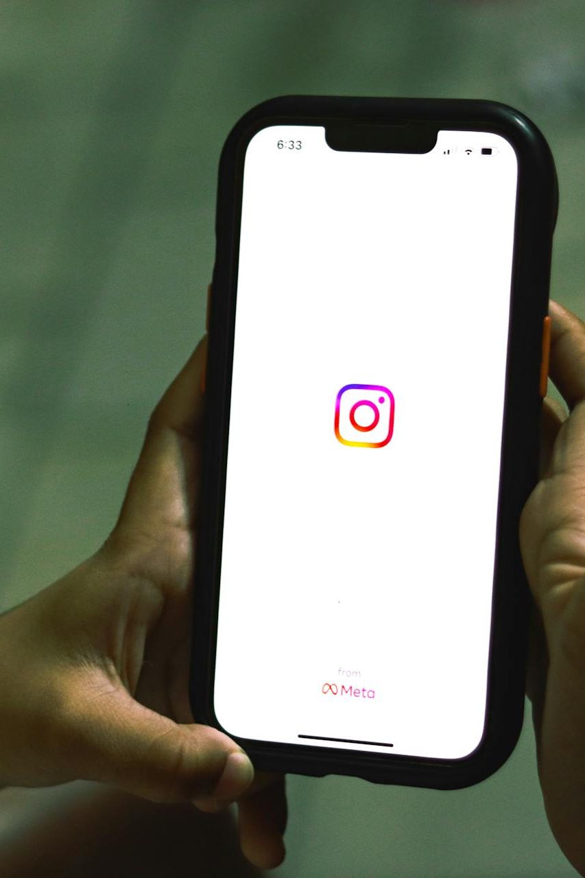 Close-up of a woman holding a smartphone displaying the Instagram app indoors.